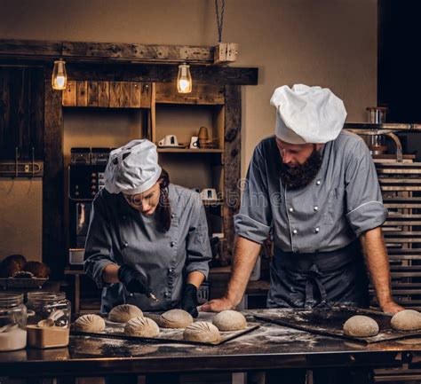 Chef Teaching His Assistant To Bake The Bread In A Bakery Stock Photo