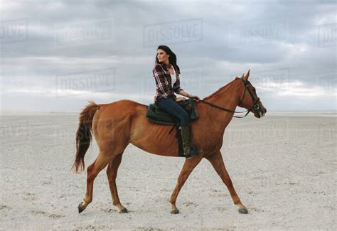 Woman Horse Ride On Beach At Sunset And Glancing Back Beautiful Female