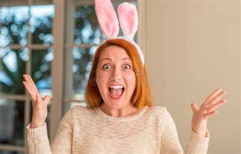 Redhead Woman Wearing Easter Rabbit Ears At Home Very Happy And Excited