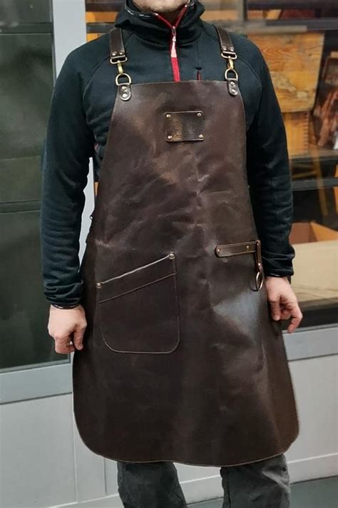 A Man Standing In Front Of A Store Wearing An Apron