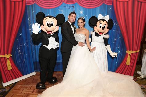 A Bride And Groom Pose For A Photo With Mickey Mouse At Their Disney