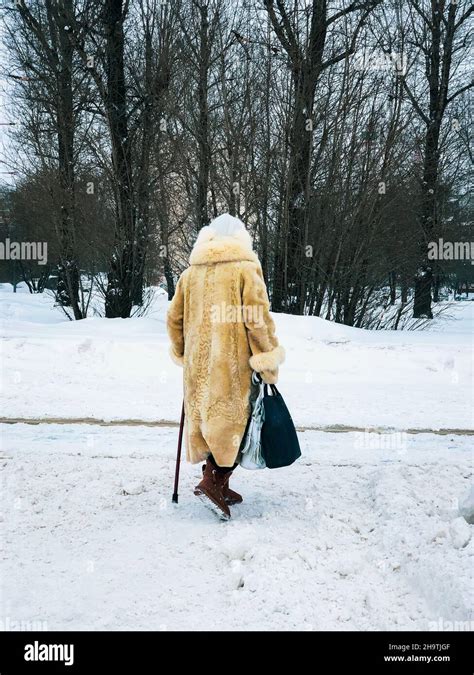 Winter Back View Of Elderly Women In Fur Coat With Bags Walking Along
