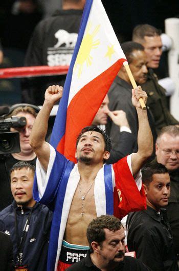 A Man Holding A Flag In The Middle Of A Boxing Ring With Other People Behind Him