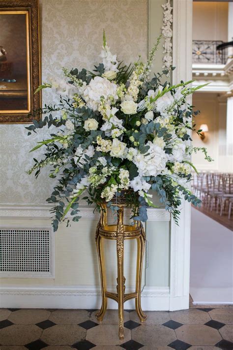 A Pedestal Of Flowers Decorating The Aisle Including White Peonies