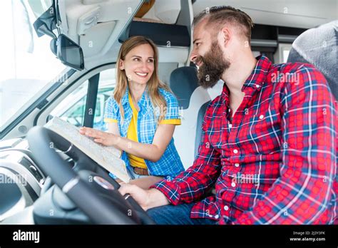 Couple at yard of RV dealer planning the trip with their camper Stock