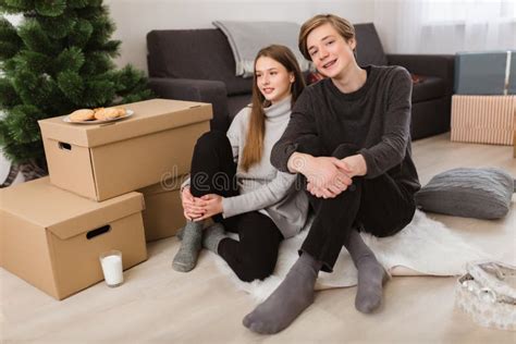 Portrait Of Beautiful Girl And Boy Sitting On Floor At Home And Happily
