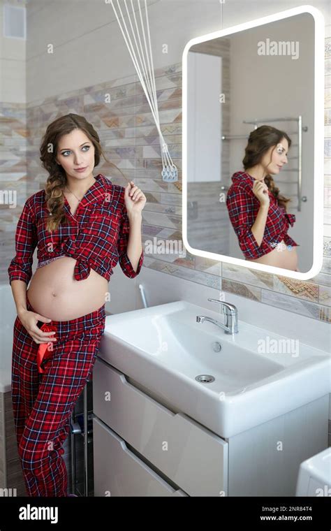 A Pregnant Woman In The Bathroom Female Dressed In Red Pajama And Open Belly Enjoying Her