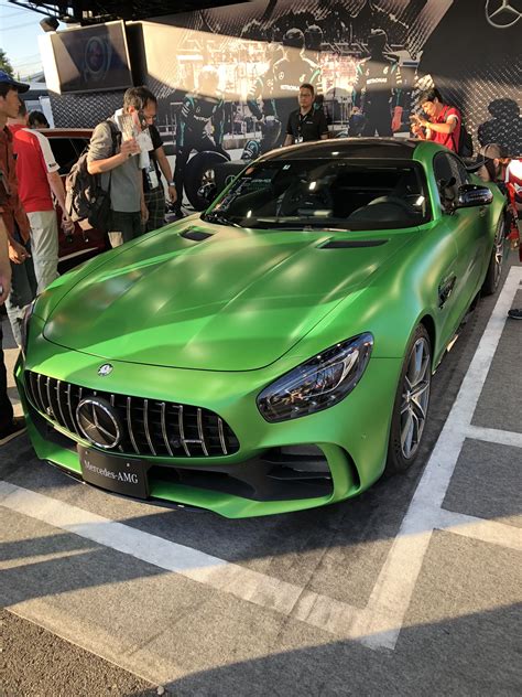 A Green Mercedes Sports Car Parked In Front Of A Group Of People