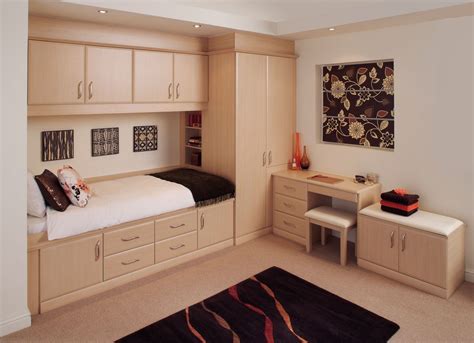 A Bedroom With A Bed Desk And Dressers In The Corner On Carpeted Flooring
