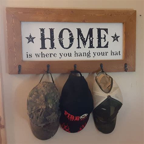 Three Hats Hanging On A Wall With A Sign Above Them That Says Home Is