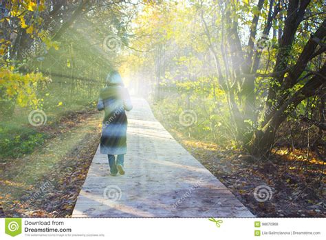 Person In A Hood Walking Toward The Light Stock Photo