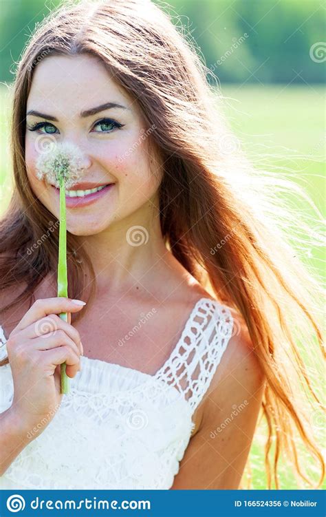 Girl In White Dress Holding A Dandelion Blooming And Smiling To You