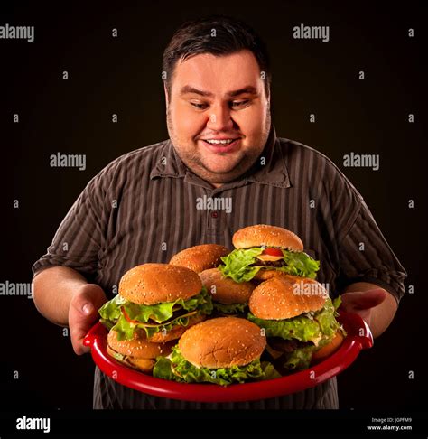 Fat Man Eating Fast Food Hamberger And Carries Treat For Friends On Tray Breakfast For