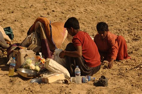 Two Men Are Sitting On The Ground With Food And Water In Front Of Their
