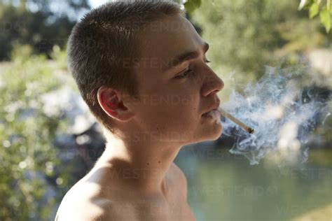 Portrait Of Teenage Boy Smoking Cigarette In Nature Stock Photo