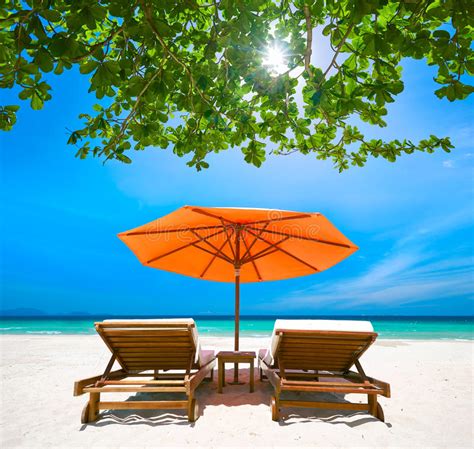 Two Deck Chairs Under A Red Umbrella On Tropical Beach