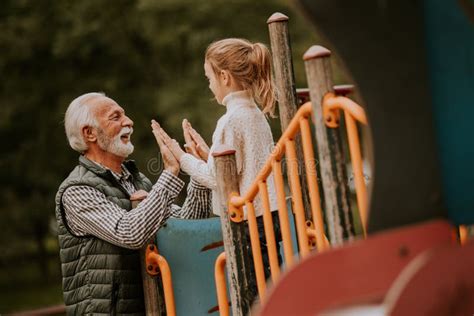 grandfather spending time with his granddaughter in park playground on autumn day stock image