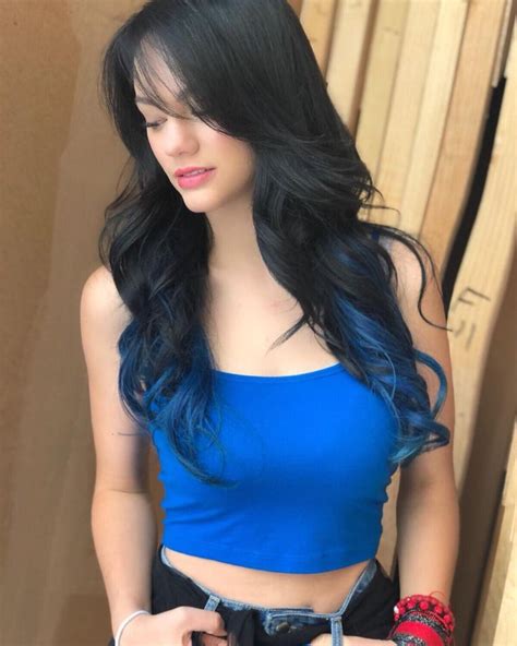 A Woman With Long Black Hair Wearing A Blue Crop Top And Holding A Cell