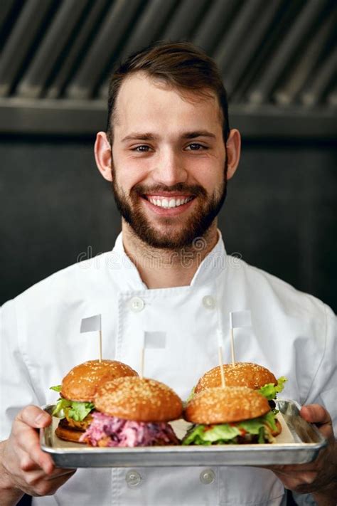 Chef With Burgers In Restaurant Kitchen Stock Photo