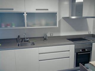 Muebles de cocina en color blanco y gris efecto cemento, dos colores que facilitan un ambiente moderno y de estilo industrial. cocina con encimera negra y muebles de madera clar ...