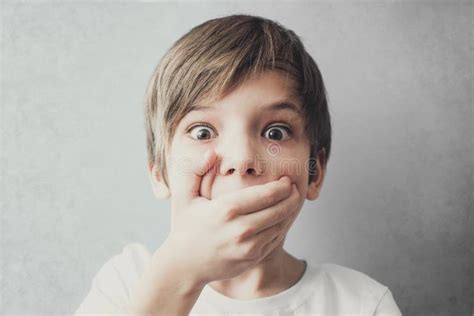 Portrait Of Frightened Boy Covering His Mouth With His Hand Stock Photo