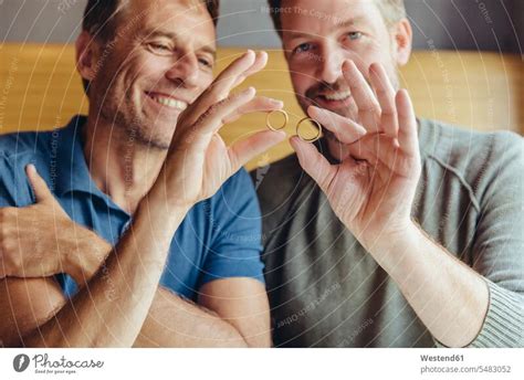 glückliches schwules paar das seine eheringe hochhält ein lizenzfreies stock foto von photocase