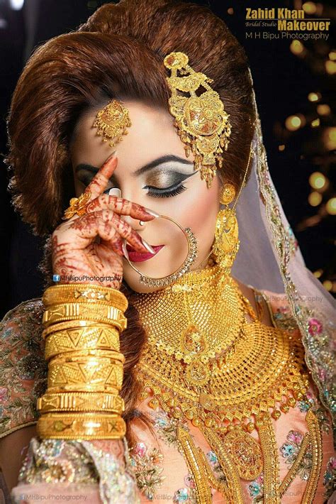 A Woman Wearing Gold Jewelry And Holding Her Hands To Her Face
