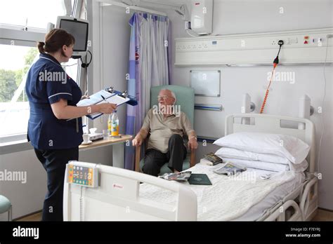 A Nurse Talks To An Elderly Patient In A Modern Uk Hospital Ward