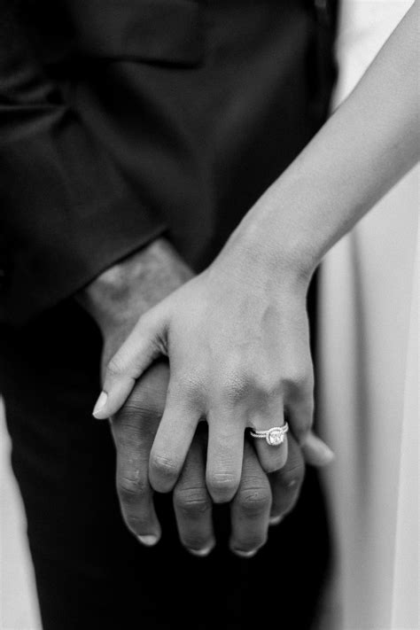 Detail Of Bride And Groom Holding Hands With Wedding Ring In Black And