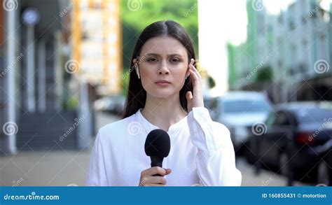 Serious Female Reporter With Microphone In Front Of Camera Breaking