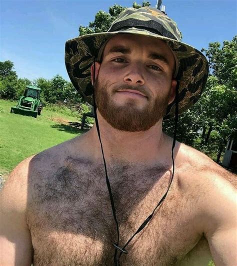 A Shirtless Man Wearing A Hat And No Shirt Standing In The Grass With