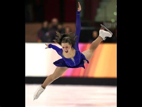 A Female Figure Skating On The Ice In A Blue Outfit And White Shoes