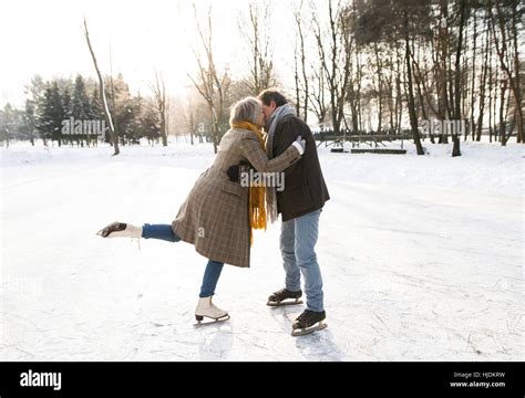 Senior Couple In Winter Nature Ice Skating Hugging And Kissing Stock