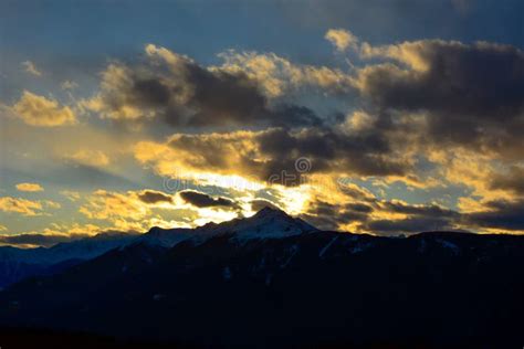 The Sun Sets Behind The Clouds In The Shadow Above The Snowy Evening