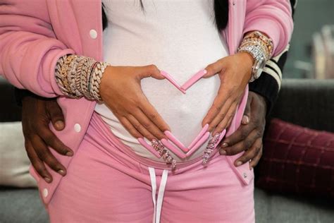 a pregnant woman in pink pants holding her belly with both hands and showing the inside of her