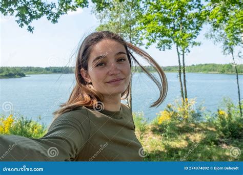 Beautiful Cheerful Young Woman Having A Good Time At The Lake On A Lovely Day Taking A Selfie