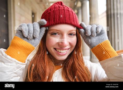 Headshot Of Happy Redhead Girl With Freckles Wears Red Hat And Gloves