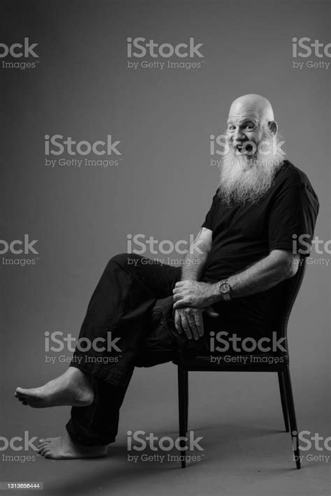 Portrait Of Man Sitting On Chair Against Wall Stock Photo Download
