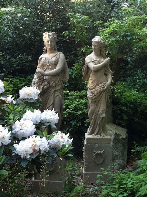 Two Statues Sitting Next To Each Other In The Middle Of Some Bushes And
