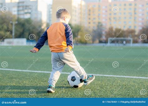 A Little Boy Plays Soccer In A City Park Gives A Pass Kicks A Ball