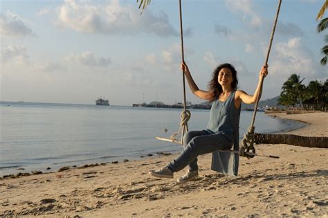 Premium Photo Girl On The Beach Rides On A Swing During Sunset