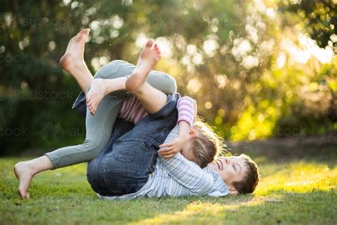 Image Of Brother And Sister Play Fighting Together On Lawn In Garden