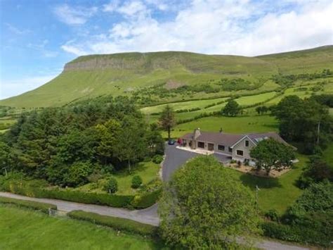 An Aerial View Of A House Surrounded By Lush Green Hills