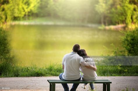 Caucasian Couple Sitting On Bench Hugging By Lake Photo Getty Images