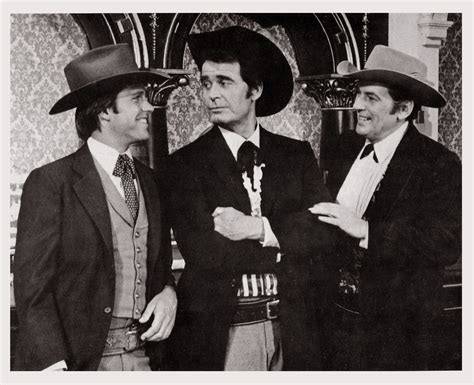 Three Men In Suits And Hats Standing Next To Each Other With One