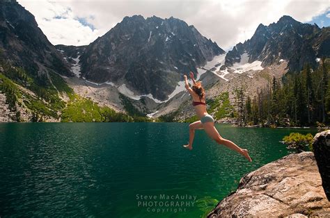 Young Woman Leaping Into The Emerald Green Water Of