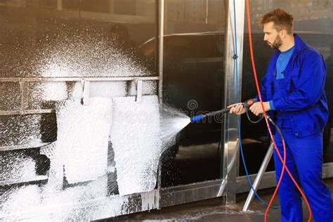 Worker Cleaning Auto Mats With High Pressure Foam Jet At Car Wash Stock