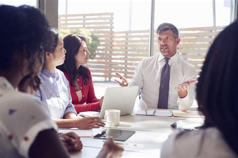 Male Manager Sits Talking To Colleagues In A Meeting Room Stock Photo