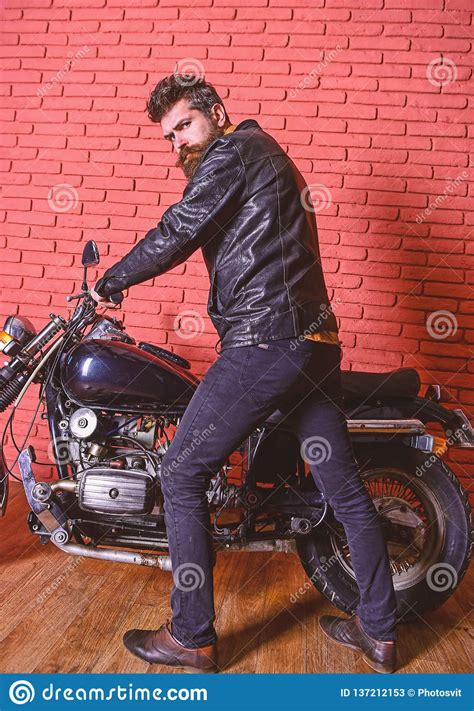 Man With Beard Biker In Leather Jacket Near Motor Bike In Garage