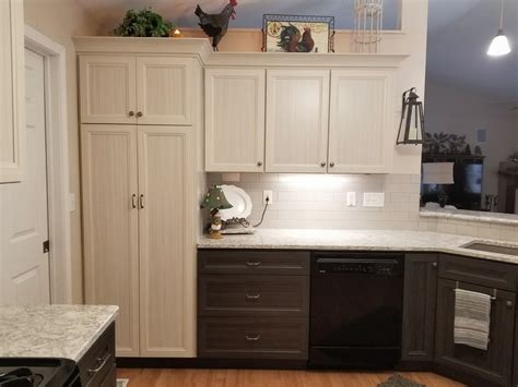 This bright and beautiful modern farmhouse kitchen incorporates a beautiful custom made wood hood with white upper cabinets and a dramatic black base cabinet from kraftmaid. Kitchen Cabinet Styles | Tuxedo Kitchen Cabinets